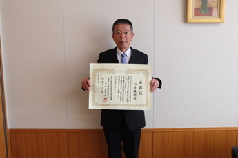 表彰状を持つ永屋校長先生の写真