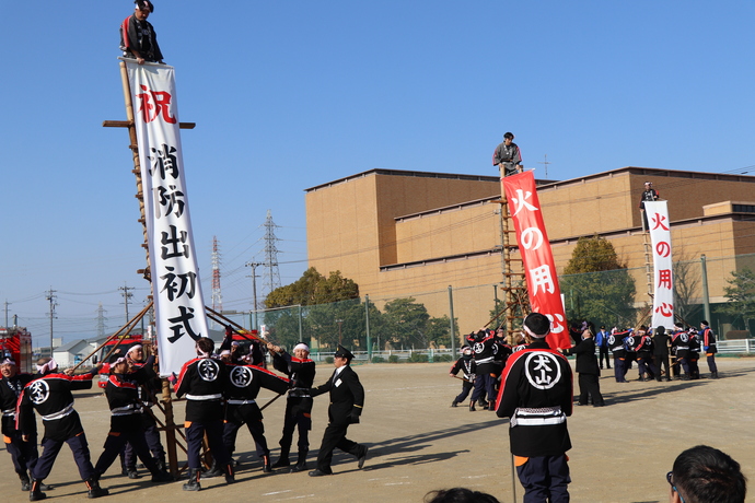 はしご乗りではしごの上から、「祝消防出初式」や「火の用心」の垂れ幕を垂らす消防団員