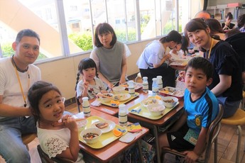 笑顔で給食を楽しむ親子の写真