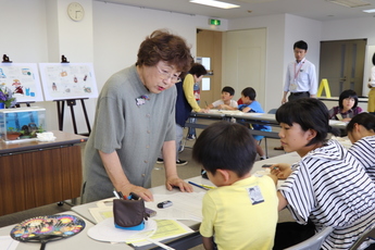 女性講師が小学生の前で説明する様子