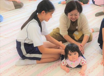 赤ちゃんにふれあう中学生の写真