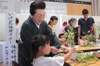 女の子が着物の女性に教わりいけ花をしている様子