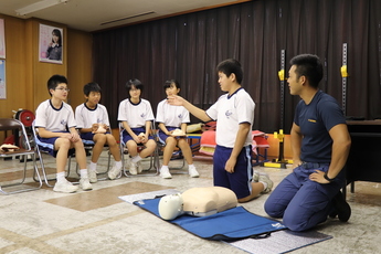 消防署員が先生役となり男子中学生が人形の前で指さし確認を行う様子