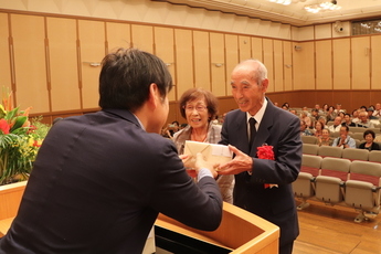 市長から記念品を渡される富塚さん夫婦