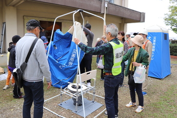 災害用トイレを組み立てる参加者ら