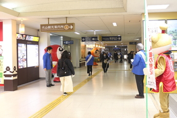 犬山駅東西連絡橋で人権擁護委員、山田市長、マスコットキャラクターがチラシを配る様子