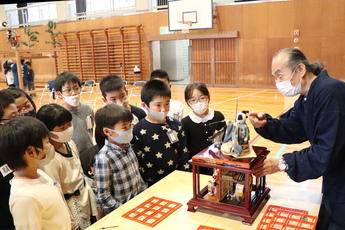 弓引き童子の説明を受ける児童ら