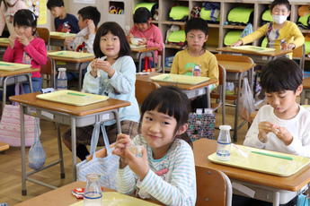 教室で自分の席で給食に出たゼリーを食べている児童ら