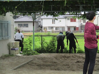 フェンス沿いの草を集める人