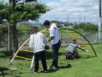 夏の日差しの下で遊具のペンキを塗る