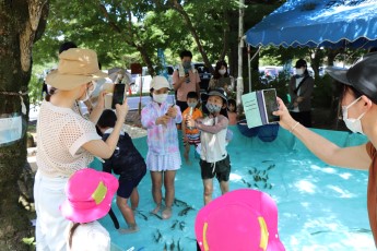 あゆをつかまえた子どもと写真を撮る親