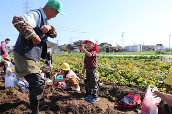 石田さんにサツマイモを見せる園児