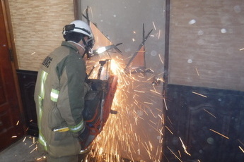 消防職員がドアを工具で切っている写真