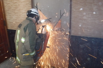 消防職員がドアを工具で切っている写真