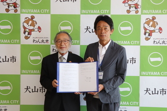 協定書を手にする佐分晴夫学長(左)と原市長(右)の写真