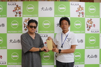 寄附金を手渡す天野年鳴さん(左)と原市長(右)の写真