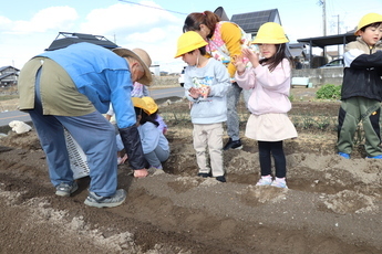 種芋を持った園児と石田さんの様子